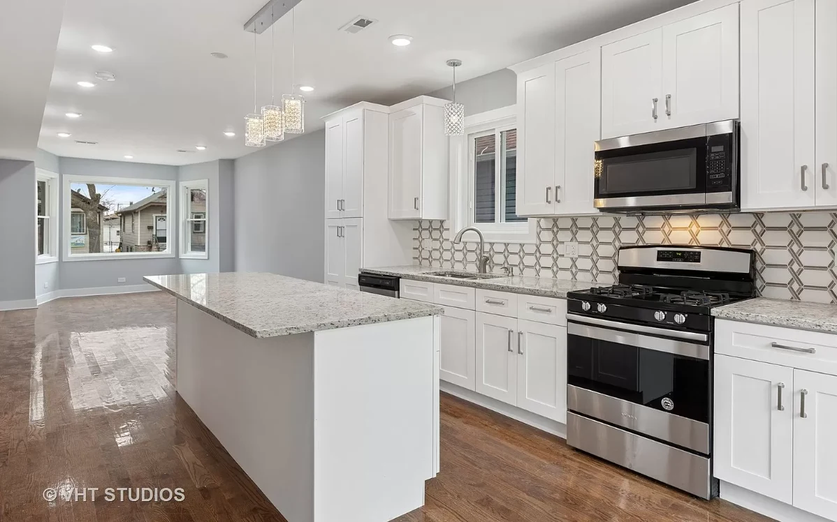 Finished kitchen with white shaker cabinetry, granite island, and patterned tile backsplash