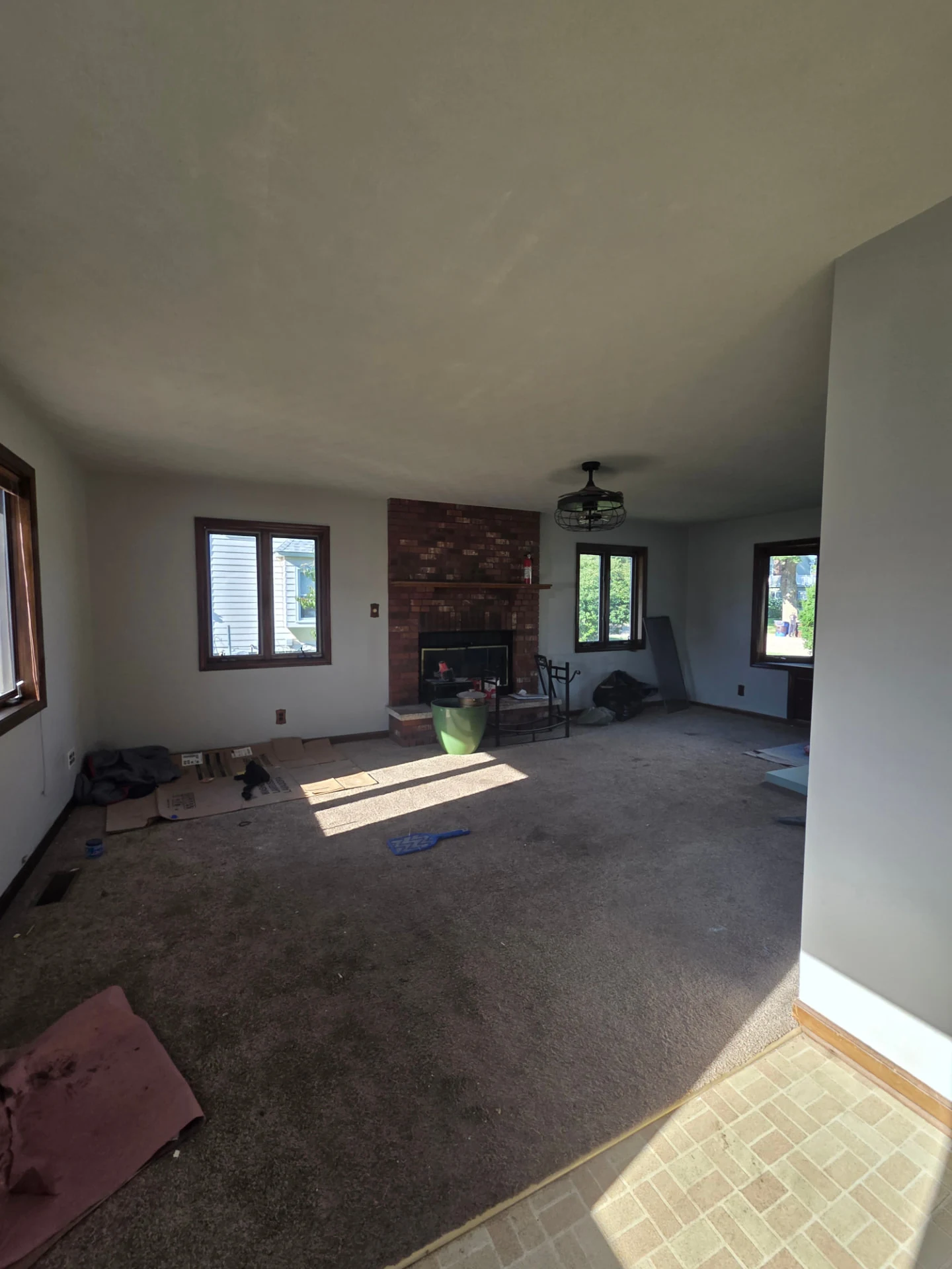Large living space with brick fireplace during renovation preparation