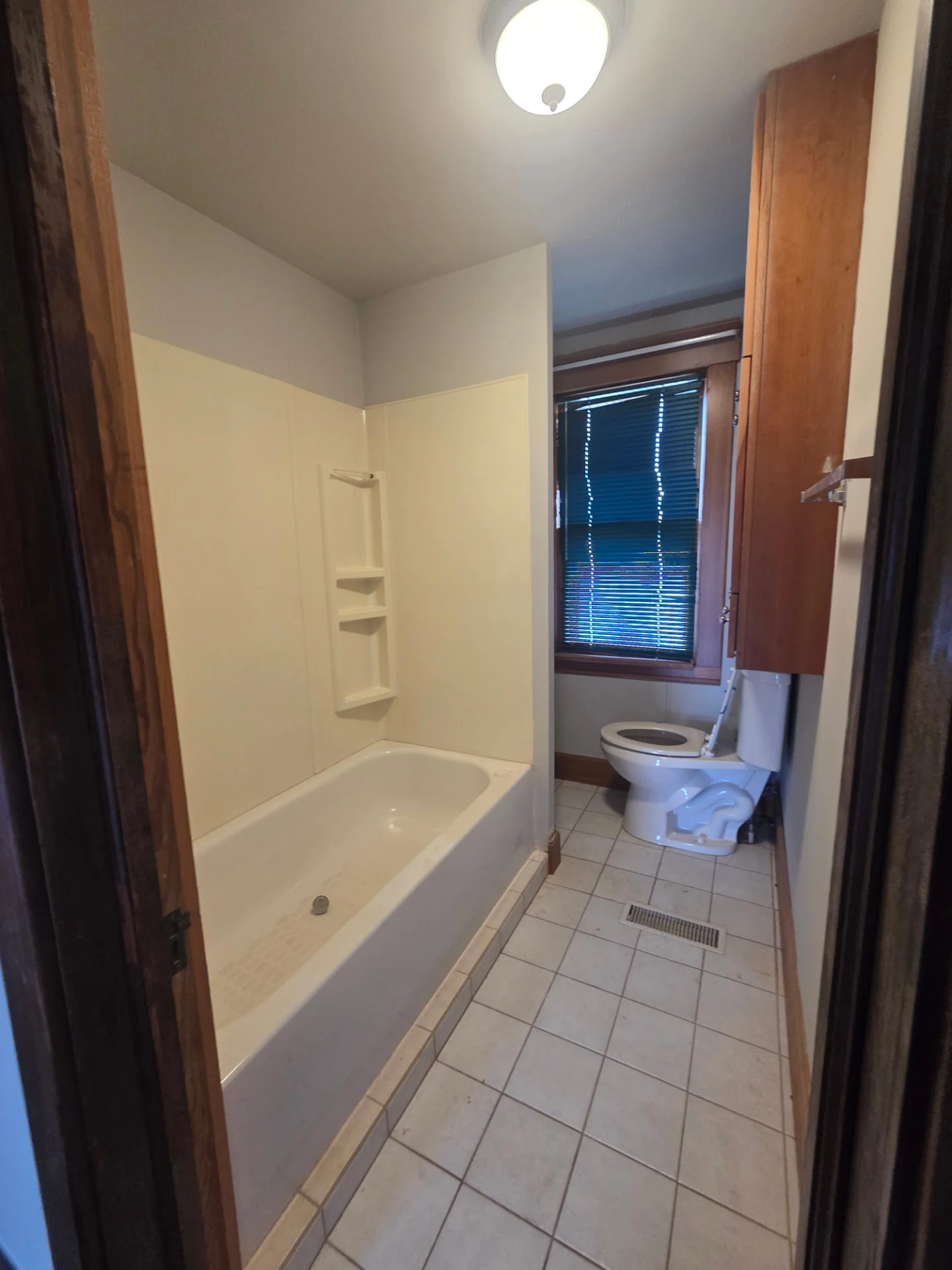 Full bathroom with tub, tile flooring and wood trim
