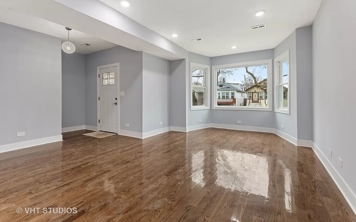 Finished living room with refinished hardwood floors and a large bay window